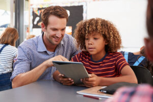 Male teacher and boy working together on a tablet
